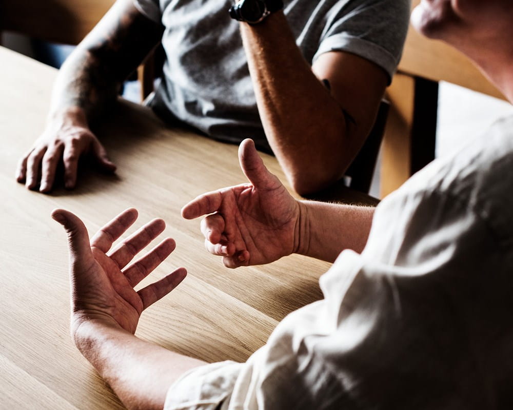 Men sitting at table having a conversation.