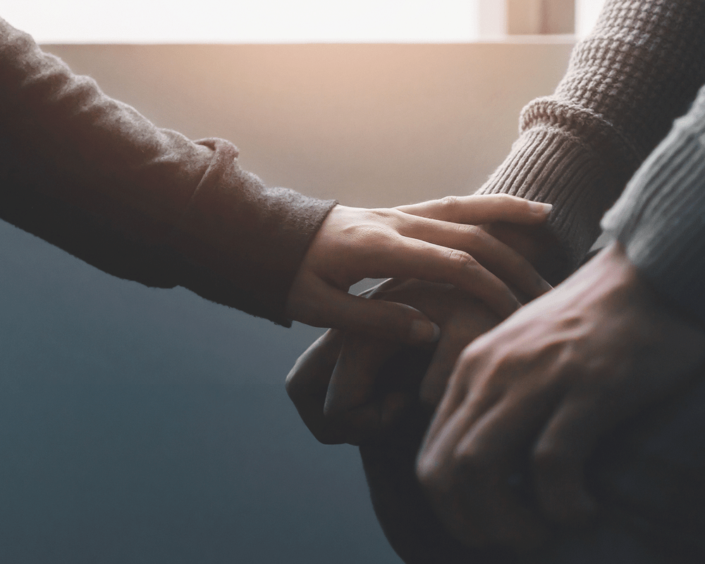 Close up of friend consolling someone, placing their hand on theirs.