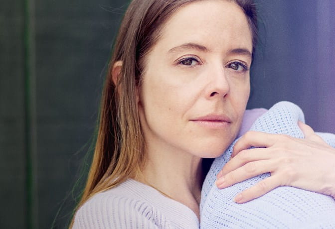 Young white woman cradling baby