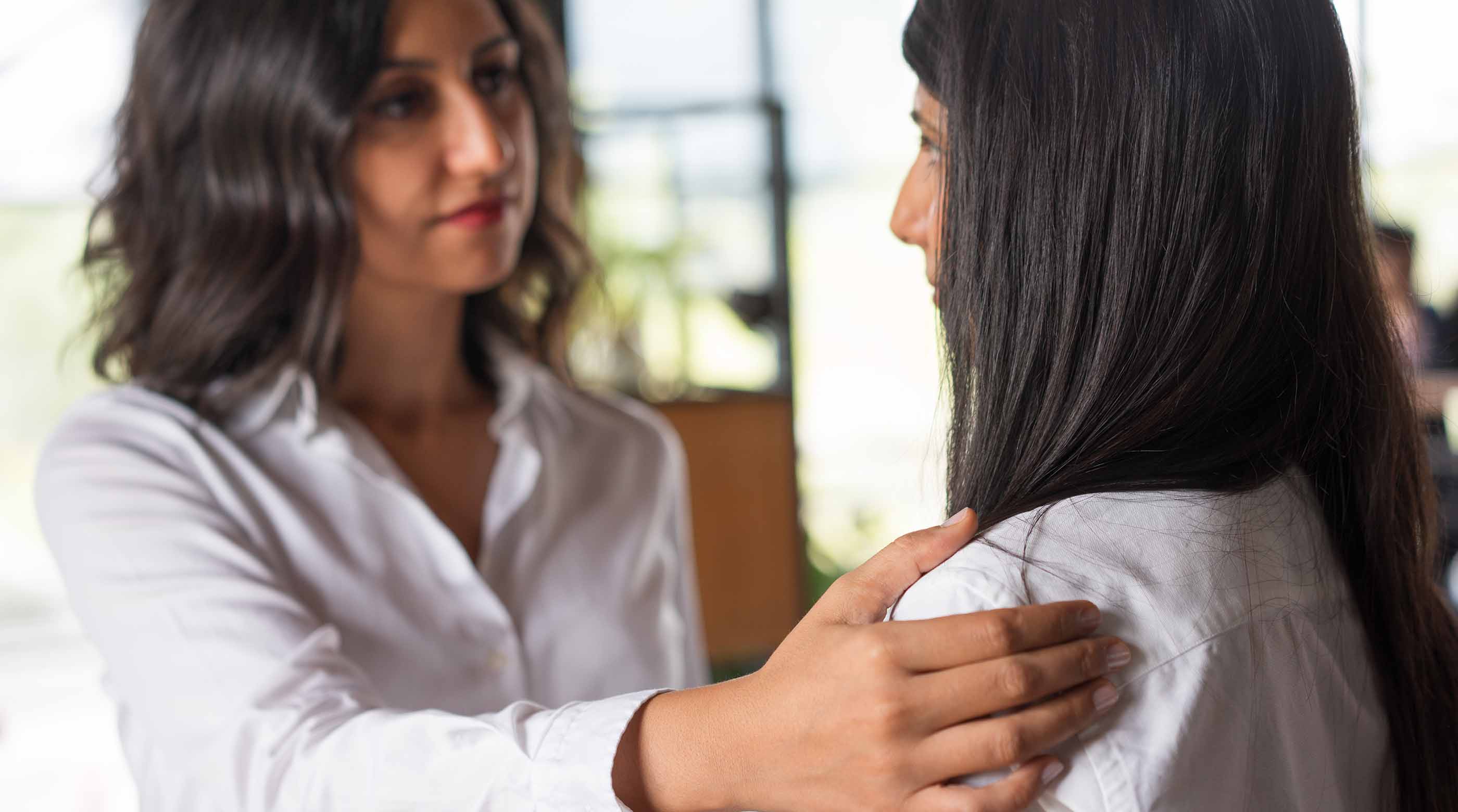 Photo of a woman holding the shoulder of another woman supportively.