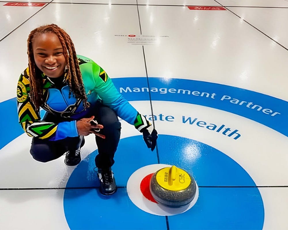 Dionne next to a curling rock in the bullseye (button).