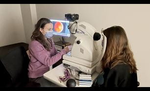 Researcher setting up retina photography with patient.