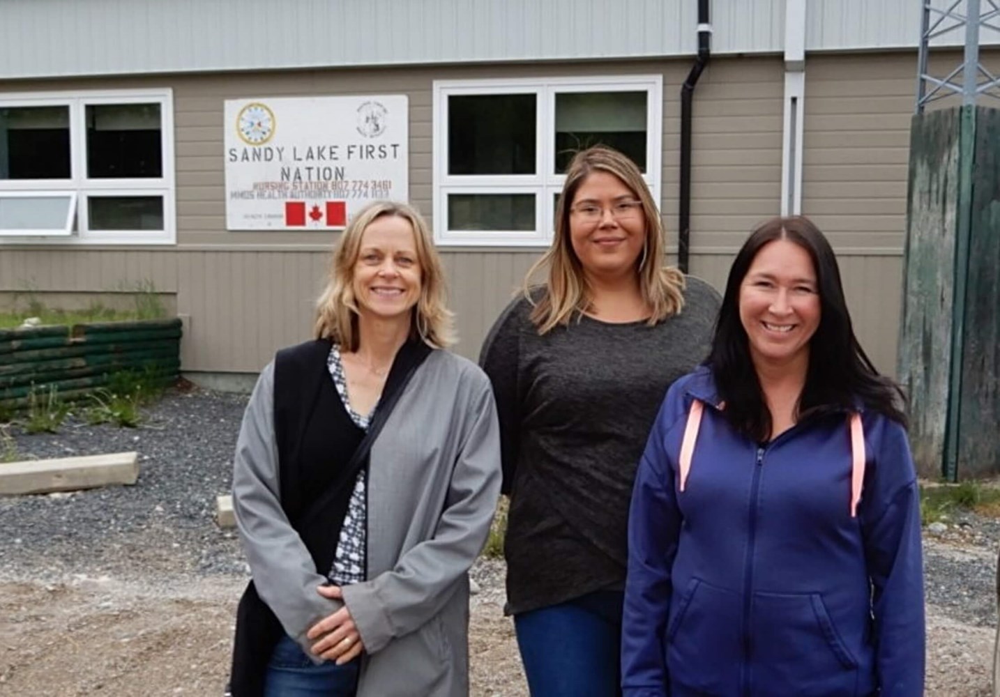 Dr. Samantha Wells, Krystine Abel and Dr. Renee Linklater outside the nursing station in Sandy Lake First Nation