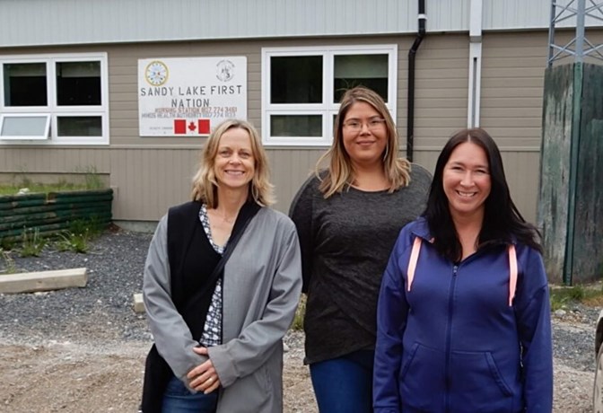 Dr. Samantha Wells, Krystine Abel and Dr. Renee Linklater outside the nursing station in Sandy Lake First Nation
