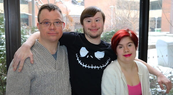 Two men and a woman with Down Syndrome smiling. 