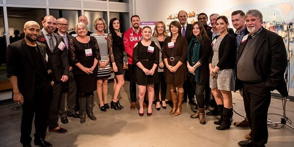 A large diverse group of men and women wearing name tags, smiling for a group picture at an event 