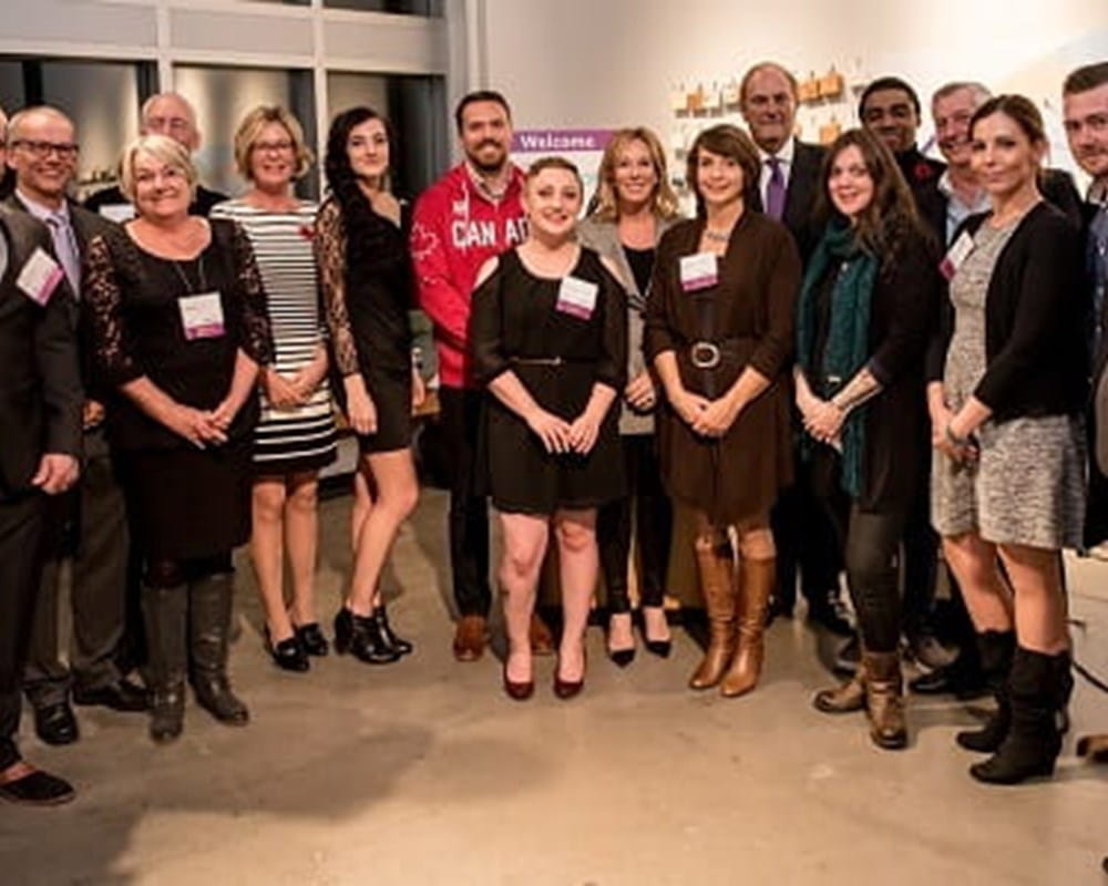 A large diverse group of men and women wearing name tags, smiling for a group picture at an event