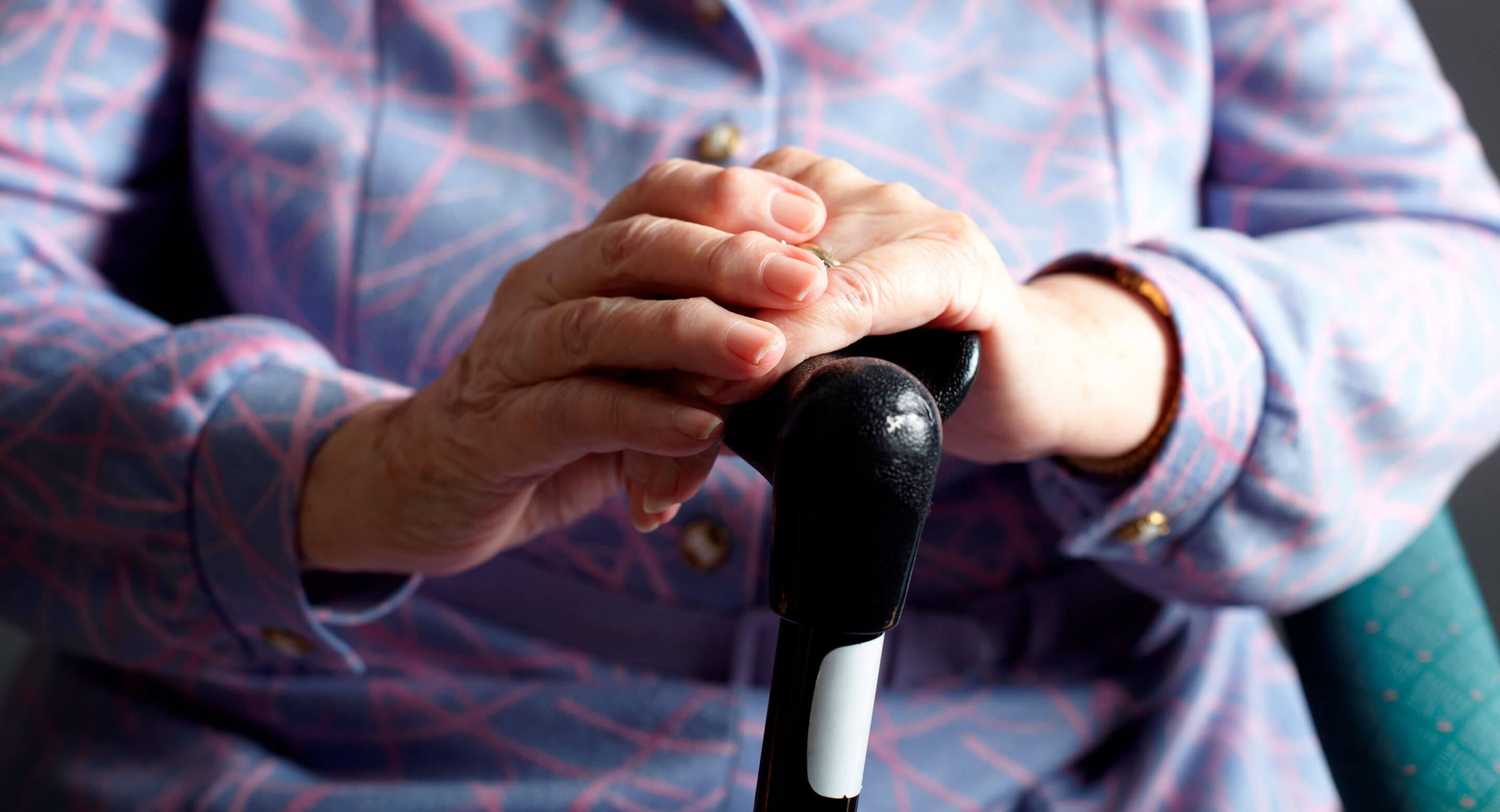 Closeup of hands of elderly woman holding cane.