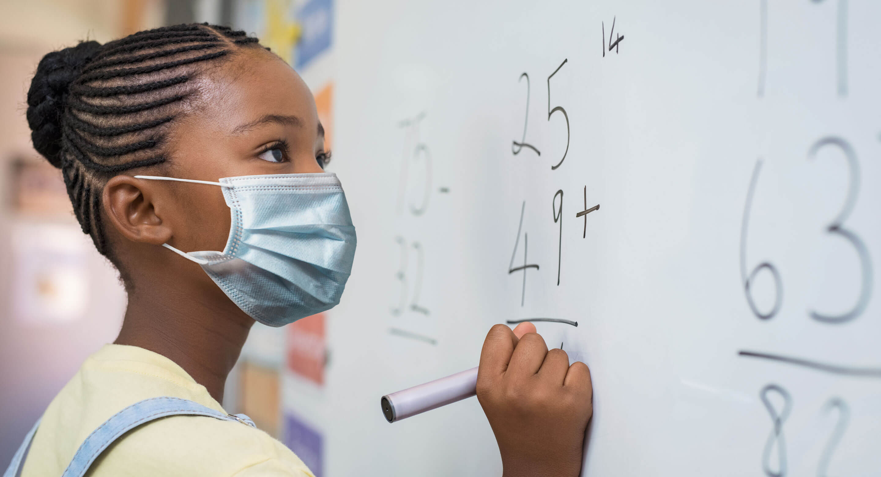 Girl wearing a mask writing on white board