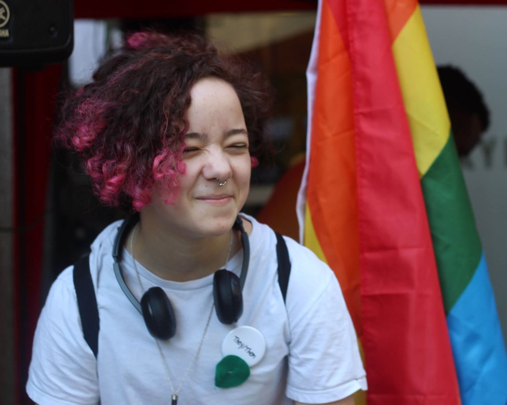 Young person in front of rainbow flag