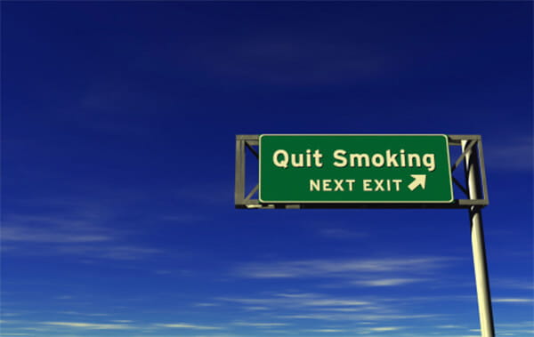 A green road sign on a tall metal pole with the phrase 