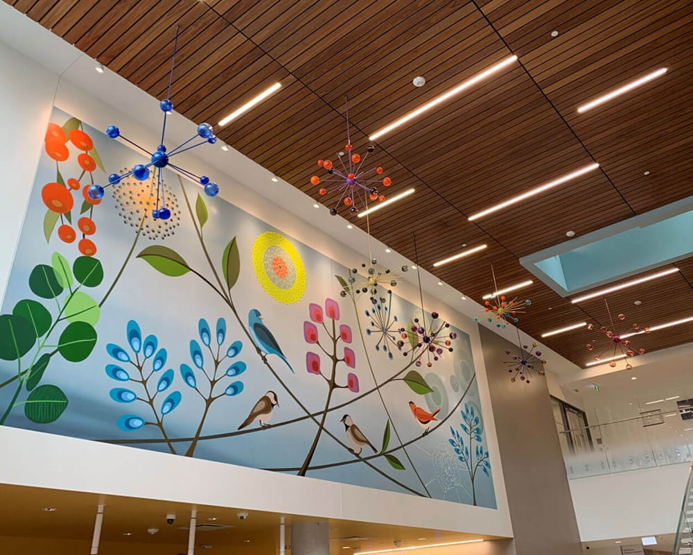 Artist: Rebecca Baird | Title: All My Relations | Location: Main lobby, Crisis & Critical Care Building | This mural and sculpture  incorporates a selection of flora and fauna imagery that will portray the fluidity and dynamic interconnectedness of all nature. The series of seven glass satellite sculptures symbolically suggest a cosmic perspective. The choice to create seven satellite sculptures reflects the importance of the ‘number seven’ within Indigenous traditional teachings. The seed-like, star-like details of the sculptures create a visually descriptive bridge connecting the concept of the cosmos to the mural imagery.