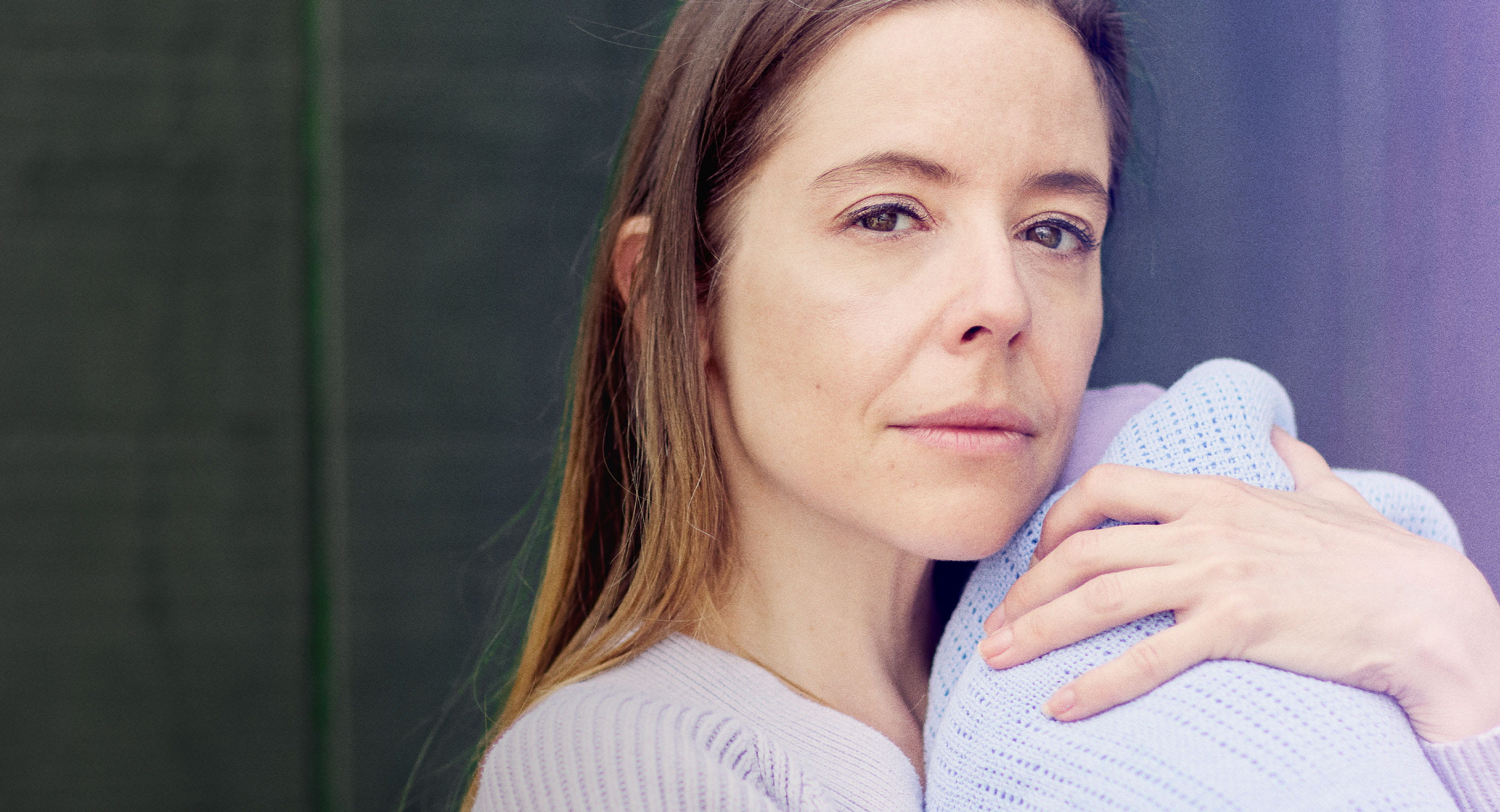 Young white woman cradling baby