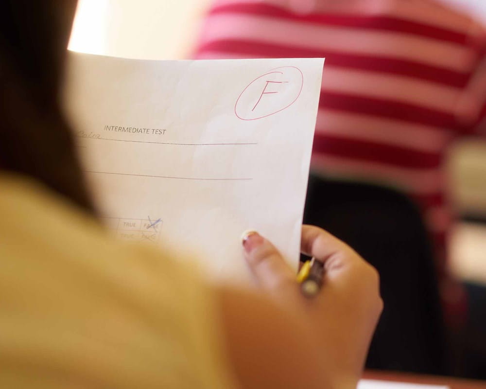Student looking at a report card with an F grade