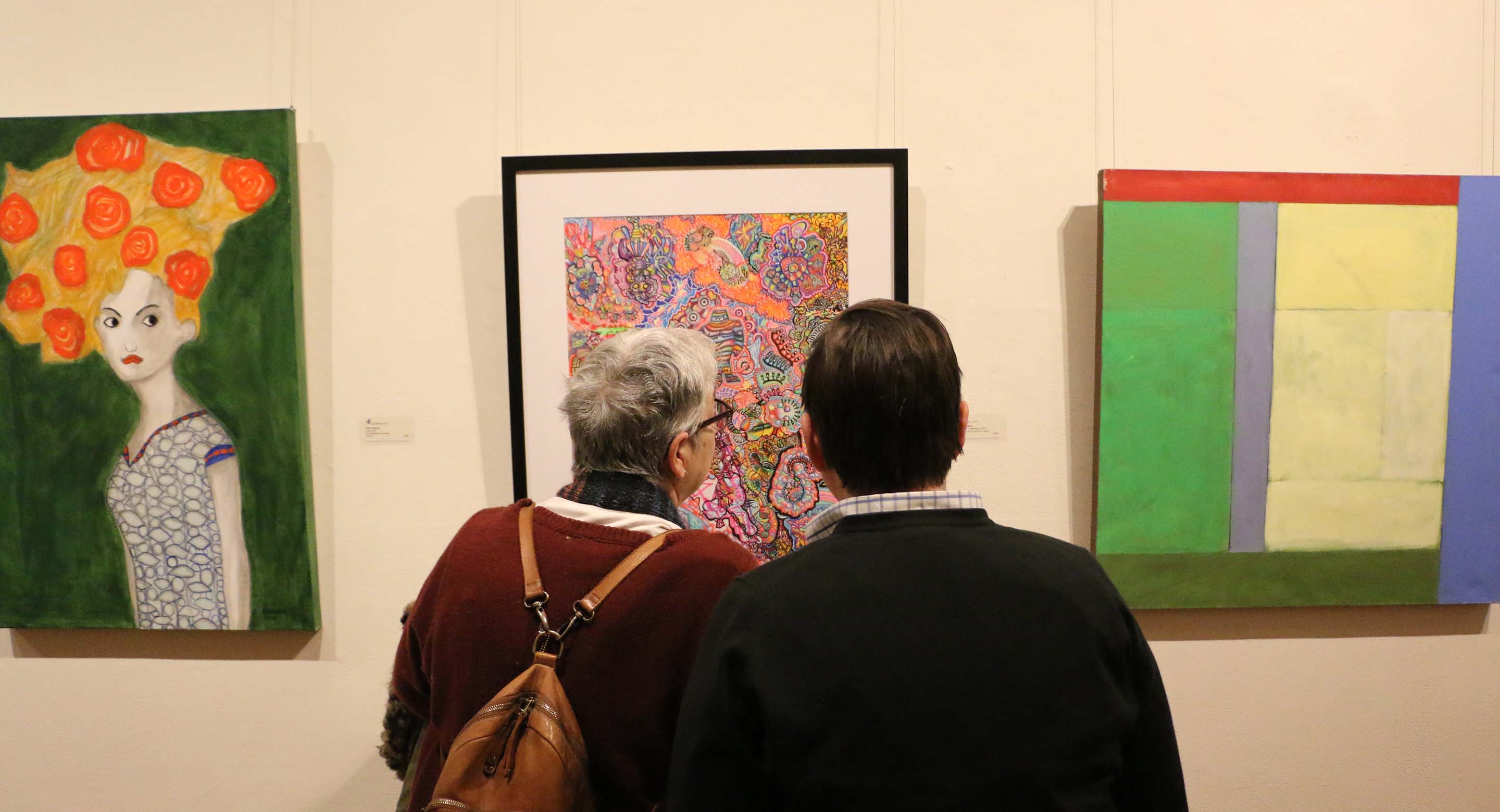 Photo of people looking at art on the wall