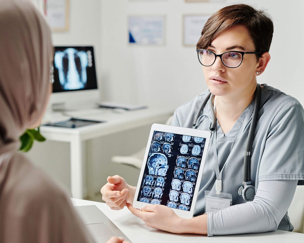 Photo of a radiologist showing brain images to a patient on a tablet
