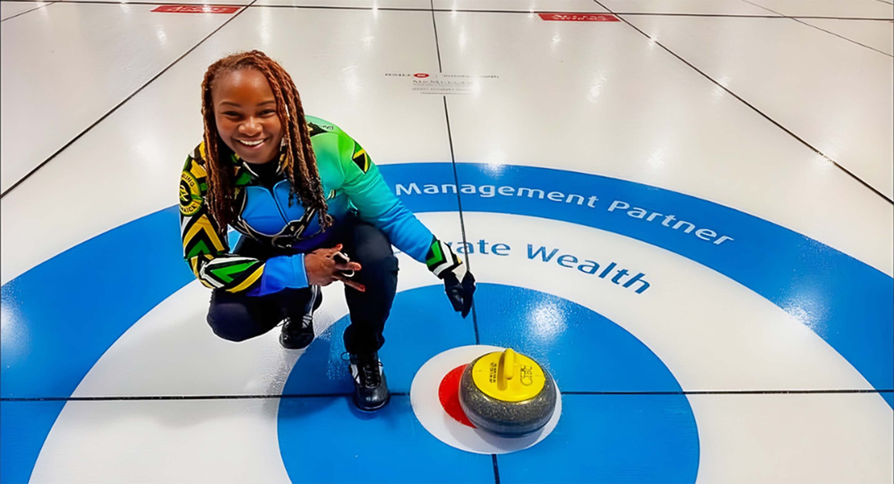 Dionne next to a curling rock in the bullseye (button). 