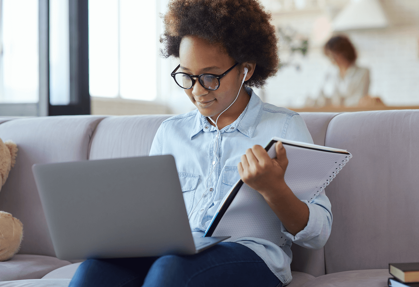 Young black girl using laptop in living room with mother in background